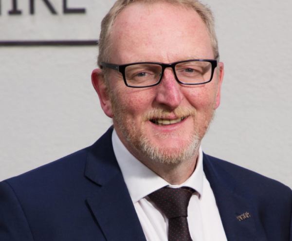 Portrait of Danny Flynn wearing glasses and a dark suit