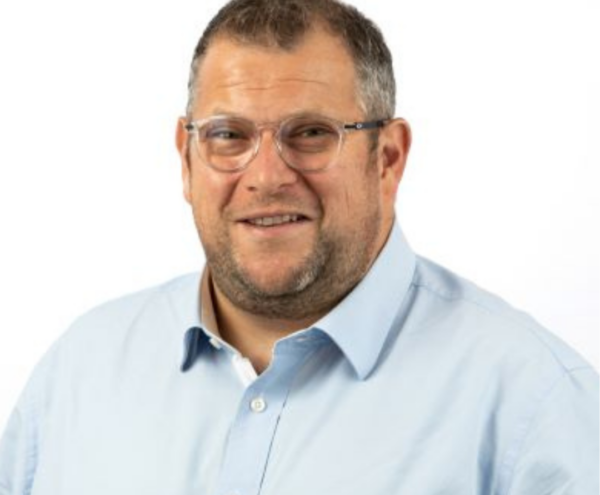 Portrait of Steve Timmis wearing round glasses and a light blue shirt